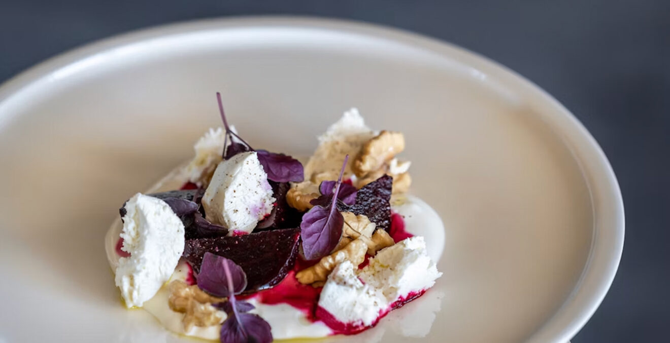 Dessertteller der FUCHSEGG ECO LODGE mit Eis, Nüssen und violetten Blättern.