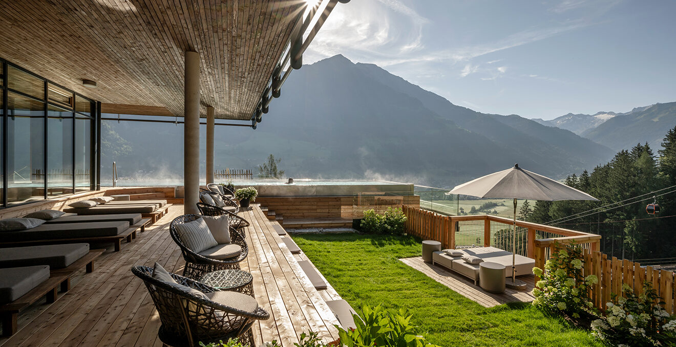 Überdachte Terrasse des Hotels Goldberg mit gepolsterten Liegen und Blick in die Bergkulisse.
