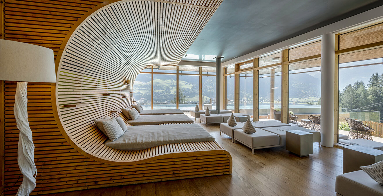 Ruheraum mit Liegefläche aus Holz und Blick in die Landschaft durch Panoramafenster.