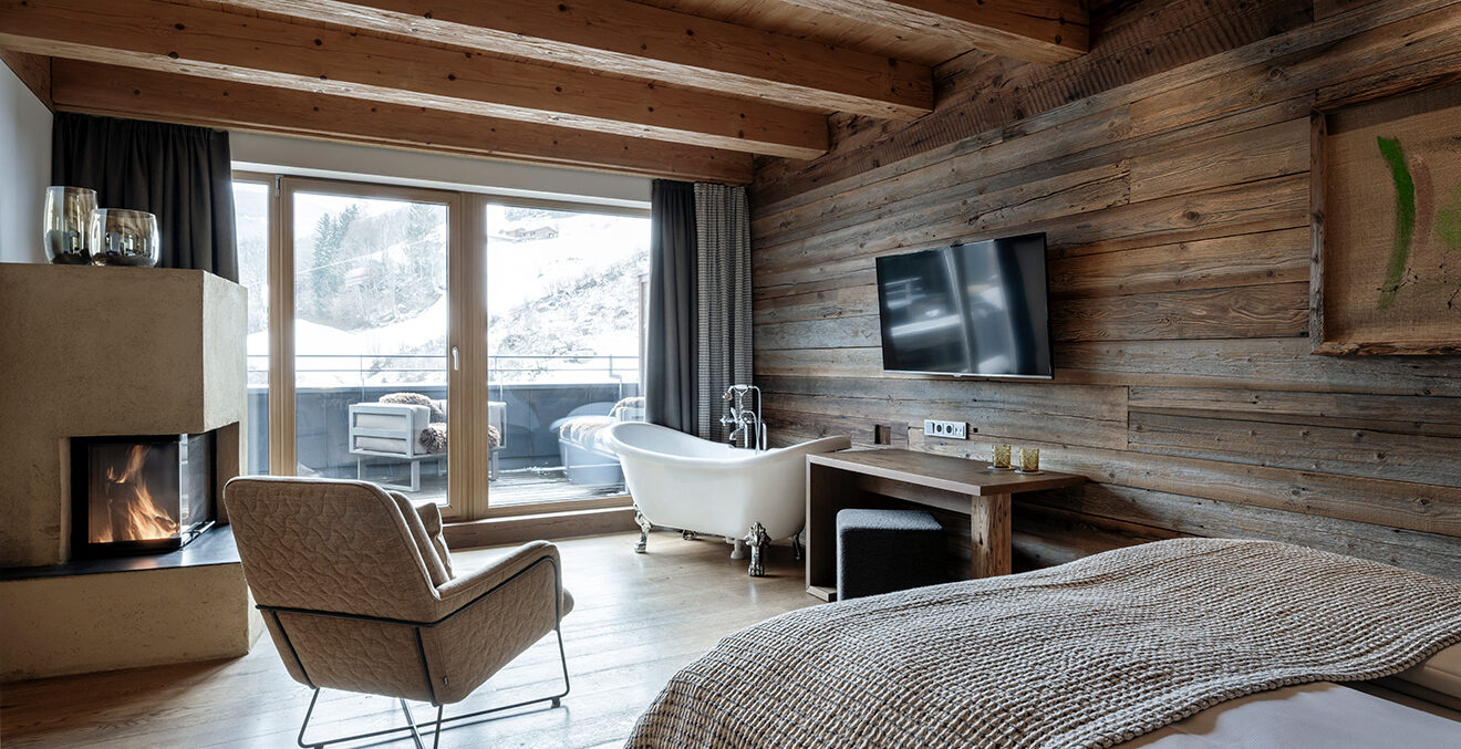 Gästezimmer mit Kamin, holzgetäfelten Wänden und freistehender Badewanne.