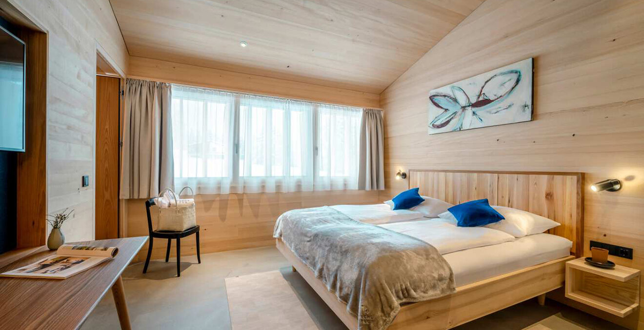 Blick in ein Gästezimmer mit heller Wand- und Deckvertäfelung.