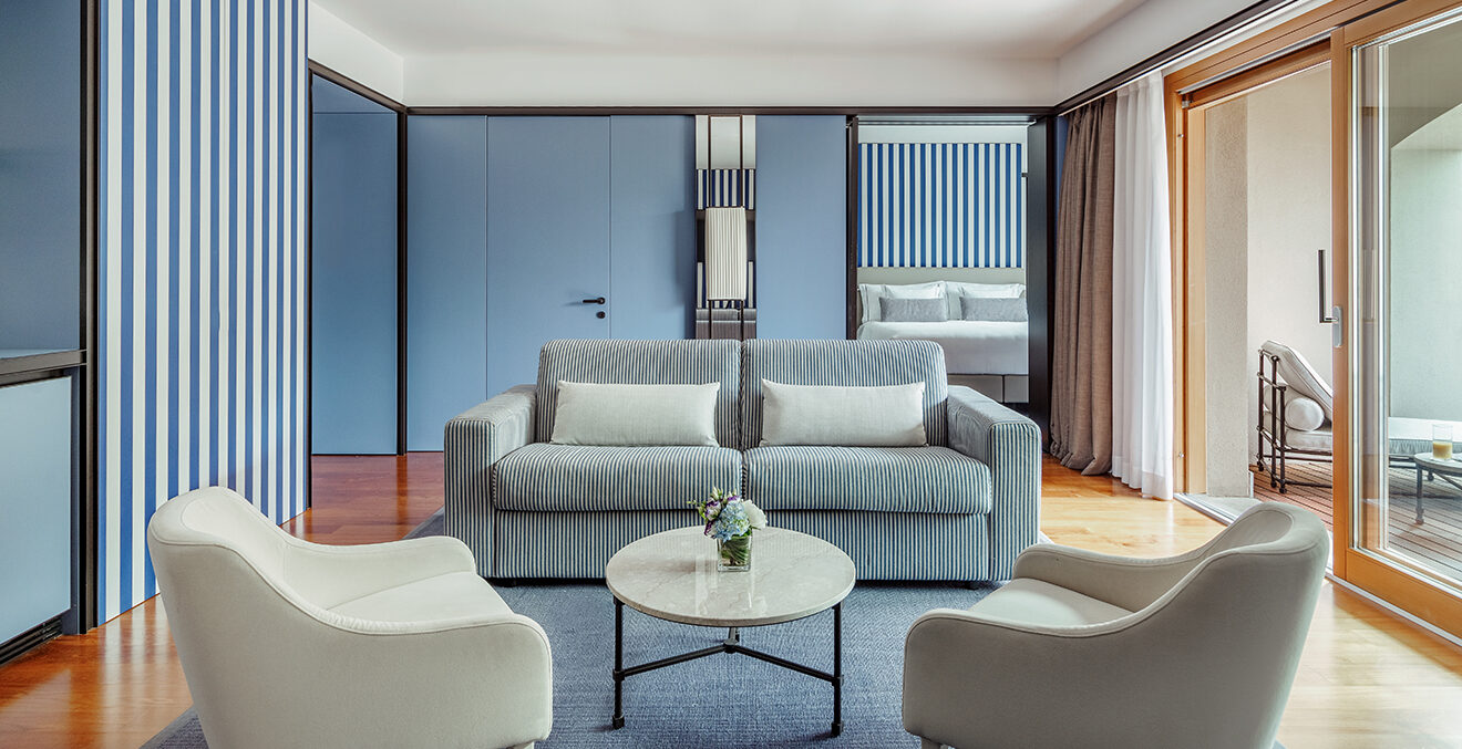 Modern eingerichtetes Zimmer mit hellen Möbeln, Sofa und zwei Sesseln.