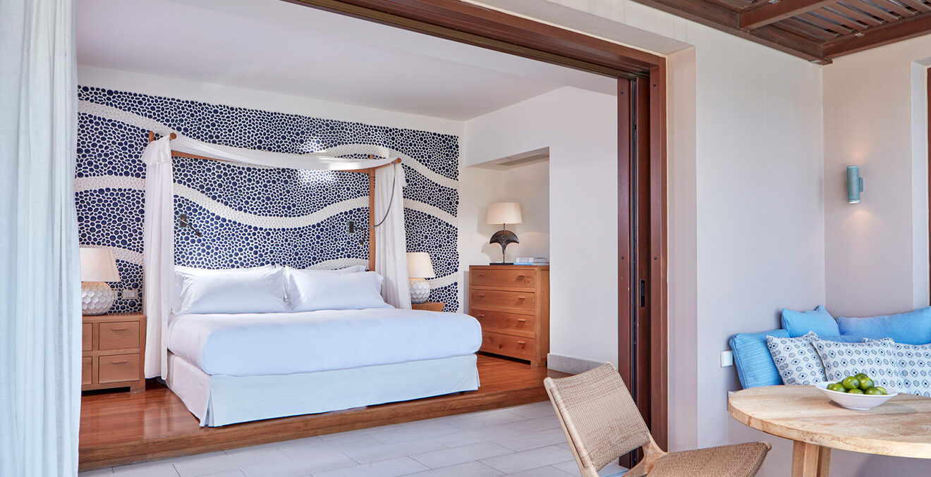 Hotelzimmer mit weißem Himmelbett und hellen Möbeln.