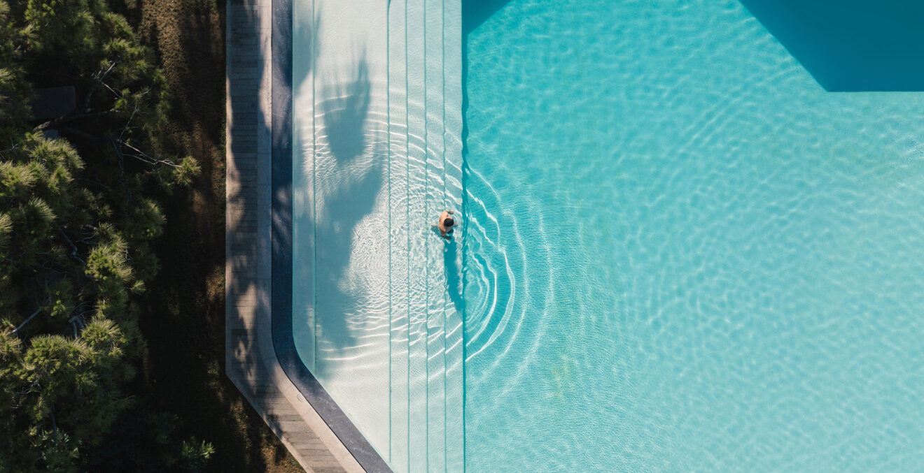 Blick aus der Vogelperspektive auf eine blau leuchtenden Pool.