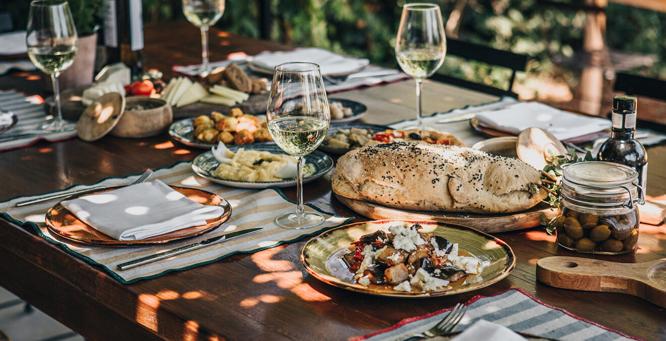 Gedeckter Tisch Tellern, Gläsern und Essen.